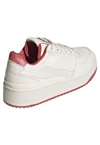 Vit lädersneaker med texturerad ovandel, röda detaljer vid hälen och fodret, tjock sula och perforerad tåbox för andningsförmåga.