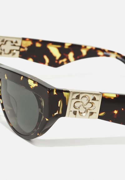 Occhiali da sole tartaruga con lenti nere, caratterizzati da un accento metallizzato dorato con un design floreale sulle aste. Montatura angolare.
