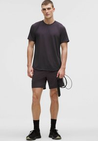 Miesten urheiluvaatteet, joissa on yksinkertainen tummanharmaa t-paita ja siihen matching-sortsit, joissa on sileä pinta. Lisävarusteena hyppynaru.