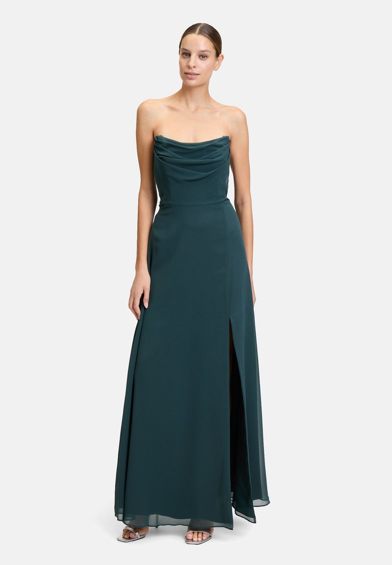 Dunkelgrünes, trägerloses Kleid mit drapiertem Oberteil, bodenlanger Optik, seitlicher Schlitze und glattem Satinmaterial. Silberelemente an der Fußbekleidung.