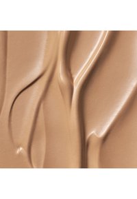 Cremige Foundation in einem warmen Bräuneton, mit glatten, fließenden Texturen, dezentem Schimmer und einem reichen, gleichmäßigen Finish.