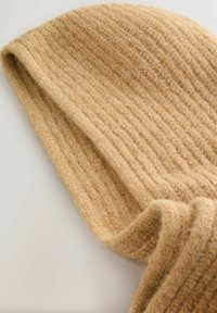 Beige, gerippte Strickmütze aus Wolle mit weicher Textur, featuring umgeschlagenen Kanten und einem lässigen Design, geeignet für kaltes Wetter.