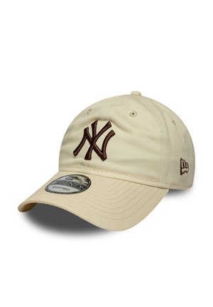 Beige justerbar baseballkasket med brun broderet "NY" logo foran og mærkelogo på siden, buet skygge og ventilationshuller.
