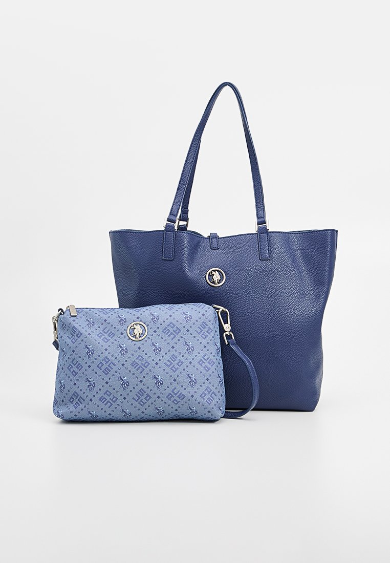 Conjunto de dos bolsas azules: una gran tote de color azul marino texturizada con asas largas y un clutch azul más pequeño con un estampado y una correa desmontable.