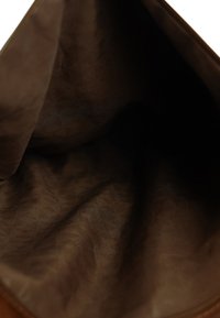 Bruine stoffen binnenkant van een tas met een zachte, gladde textuur en een subtiele glans. Het materiaal lijkt duurzaam, zonder zichtbare patronen of hardware.