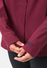 Giacca bordeaux con accenti grigi a contrasto, tessuto strutturato e polsini regolabili con Velcro per una vestibilità sicura.