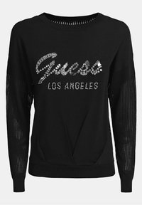 Zwarte trui met mouwen van mesh, voorzien van een rhinestone "Guess Los Angeles" logo aan de voorkant. Gebreide stof met geribbelde manchetten en zoom.