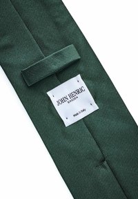 Grön diagonalt randig slips med en slät textur, som har en vit etikett med texten "JOHN HENRIC SWEDEN" och "Made in Italy."