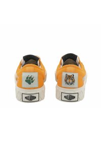 Pomarańczowe płócienne trampki z białymi gumowymi podeszwami, z haftowanymi naszywkami przedstawiającymi: tygrysa oraz odcisk łapy na pięcie.
