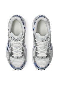 Bílé sportovní boty s (stříbrnými) akcenty, prodyšnou síťovinou, modrými detaily po stranách a tradičními šněrováním. Model: ASICS Gel-1130.