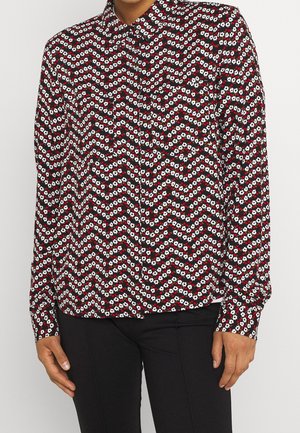 Red, white, and black patterned button-up shirt featuring a zigzag floral design, long sleeves, and a collar. Fabric is lightweight and smooth.