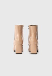 Μπέζ δερμάτινα μποτάκια μέχρι τον αστράγαλο με τετράγωνη μύτη, χοντρό τακούνι και φερμουάρ στο πλάι; λεία υφή με γυαλιστερή επιφάνεια.