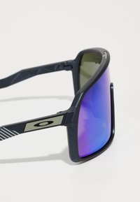 Sport-Sonnenbrillen mit schwarzem Rahmen, graduierten blauen und grünen Gläsern, strukturierten Bügeln und einem metallischen Logoakzent an der Seite.
