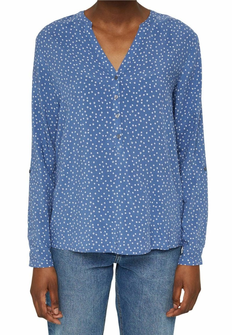 Camicia blu a maniche lunghe con scollatura a V, caratterizzata da pois bianchi, dettagli con bottoni sul davanti e una vestibilità rilassata.