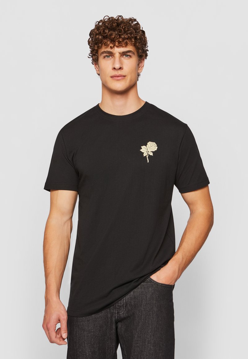 Black cotton t-shirt featuring a gold rose graphic on the left chest, short sleeves, and a classic crew neck design.