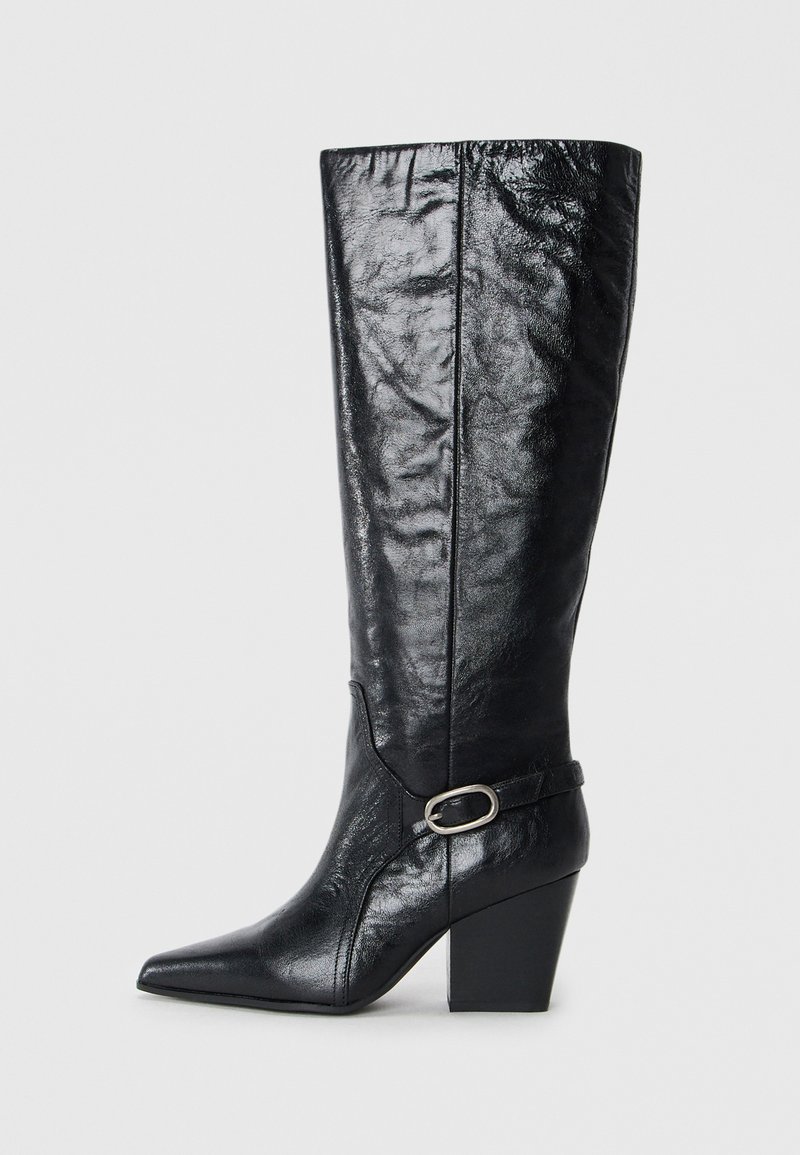 Botas negras hasta la rodilla hechas de cuero brillante, con punta afilada, forma estructurada y una correa decorativa con una hebilla de plata.