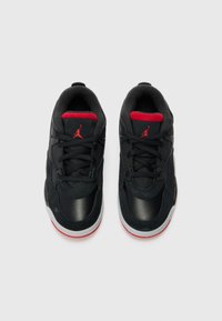 Chaussures de sport noires avec une tige en cuir lisse et en daim. Accents rouges sur la languette et le logo. Semelle en caoutchouc blanche avec une semelle extérieure rouge.