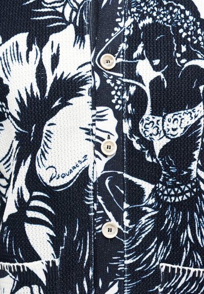 Črno-belo teksturirano blago z motivom tropskih cvetov in plesalke hula, s belimi gumbi in vidnim podpisom "Dsquared2".