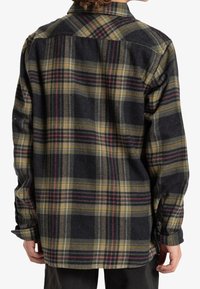 Camicia flanella a quadri nei toni del nero, verde oliva e bordeaux, con vestibilità rilassata, maniche lunghe e polsini abbottonati. Tessuto leggero.