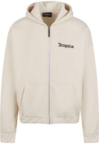 Cremefarvet zip-up hættetrøje med en frontlomme og broderet "Dropsize" logo i sort. Har snøre ved hætten og ribbede manchetter.