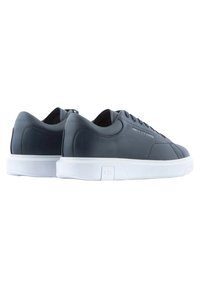 Navy leather sneakers with white rubber sole, round toe, and flat laces. Features subtle branding on the side and smooth texture.