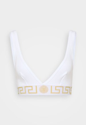Bralette blanche avec un décolleté en V profond, présentant une bande à motif doré et un détail de logo central, fabriqué en tissu doux.