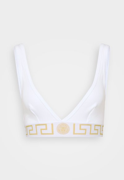 Balts bralets ar dziļu V veida kakla izgriezumu, ar zelta rakstu joslu un centralizētu logotipa detaļu, izgatavots no mīksta auduma.