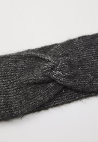 Dark gray knitted fabric headband with a twisted knot design in the center, laid flat on a white surface.