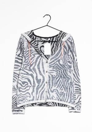 Long-sleeve, button-up hoodie with gray and white zebra stripes, orange drawstrings, hanging on black hanger with white tag on collar.