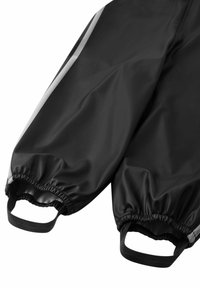 Black waterproof pants with elastic cuffs, reflective stripe detail, and side handles for easy wear. Smooth texture and durable material.