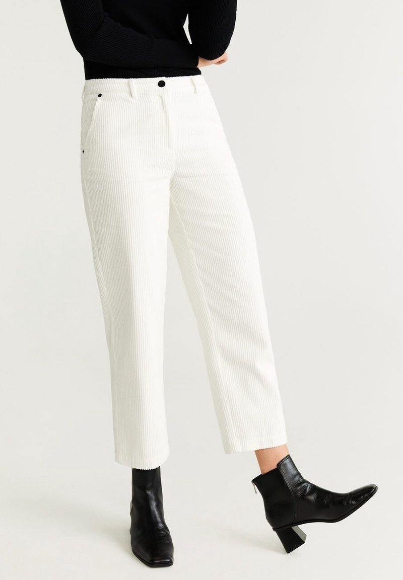 Bílé kordurové kalhoty se střih bez příkrá, s bočními kapsami a vysokým pasem, doplněné černými kotníkovými botami.