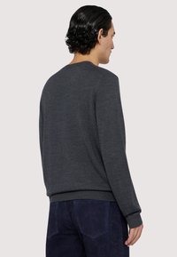 Grå tröja gjord av ett mjukt stickat tyg, med rund halsringning och ribbade ärmslut. Baksidan är slät utan synliga mönster eller detaljer.