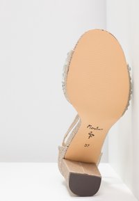 Sandale à talons hauts dorée pailletée avec une bride transparente et une semelle brune texturée. Taille 37 indiquée sur la semelle intérieure.