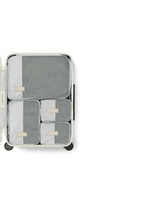 Hartschalenkoffer in Creme mit vier grauen Packwürfeln. Die Würfel verfügen über ein Netzdesign und kleine, gekennzeichnete Patches zur Organisation.