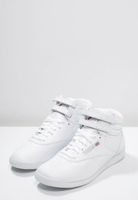 Witte hoge sneakers van glad leer, met twee verstelbare bandjes, geperforeerde neusontwerp en een gestructureerde zool.