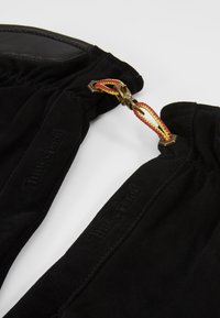 Guanti in suede nero con dettagli in pelle, dotati di un clip dorato e un cordino rosso-giallo. Logo "Timberland" impresso sul tessuto.