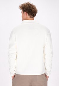 Witte fleecejack met een kraag, lange mouwen en een relaxte pasvorm. Beschikt over een gladde textuur en een onbeperkt achterontwerp.