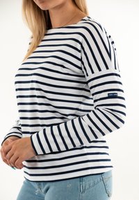Maglietta a maniche lunghe a righe blu navy e bianche realizzata in tessuto leggero, con scollatura rotonda e un piccolo logo sulla manica.