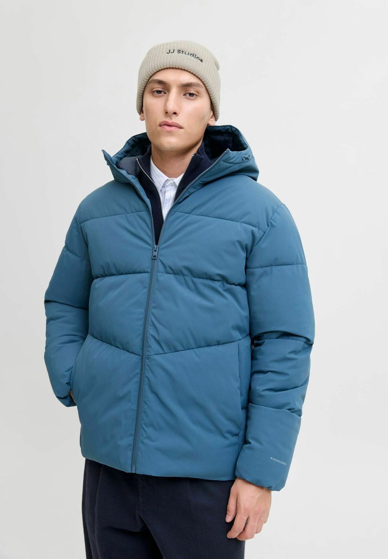Teal pufferjakke med hætte, med lynlåslukning, vandret quiltet tekstur og ribbet beige hue med logo.