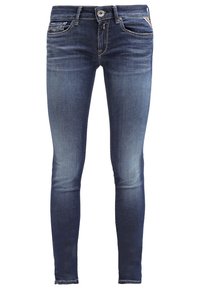 Jeans de denim ajustados en azul oscuro con detalles desgastados, cinco bolsillos y cierre de cremallera. Presentan costuras en contraste y un diseño decorativo en el bolsillo trasero.