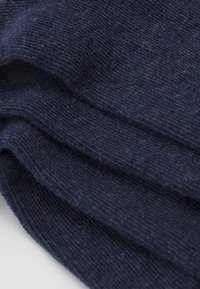 Tessuto lavorato a maglia blu navy con una texture morbida, che presenta una leggera coste e piccoli puntini chiari. Il materiale sembra avere un peso medio e cade in modo fluido.