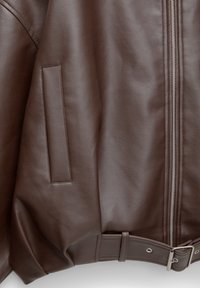 Giacca in pelle marrone con una texture liscia, chiusura con zip nella parte frontale, un dettaglio con tasca rettangolare e un orlo con cintura.