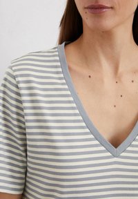Striped V-neck t-shirt in light gray and cream, made from soft cotton. Notable for its short sleeves and contrasting neckline trim.