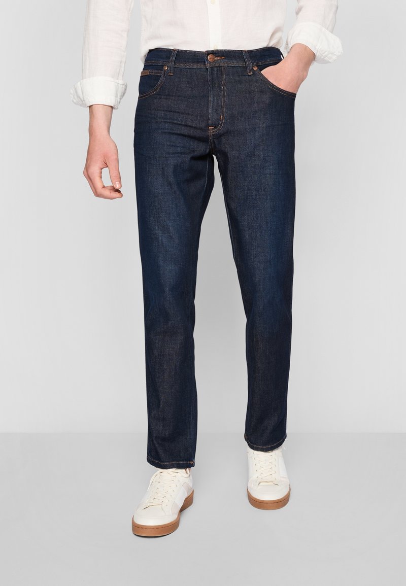 Mörkblå denimjeans med rak passform, ton-i-ton sömnad, fem fickor och en klassisk knappstängning i midjan.