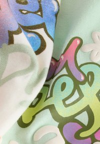 Tissu doux avec un imprimé coloré et abstrait de style graffiti dans des tons pastel de bleu, vert, rose et violet sur un fond clair.