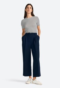 Striped short-sleeve top with round neckline, paired with navy wide-leg trousers featuring side pockets, complemented by white sneakers.