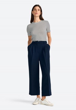 Striped short-sleeve top with round neckline, paired with navy wide-leg trousers featuring side pockets, complemented by white sneakers.