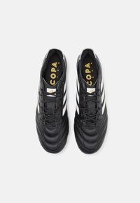 Black soccer shoes with a smooth leather upper, featuring three white stripes, a padded design, and a yellow logo inside.