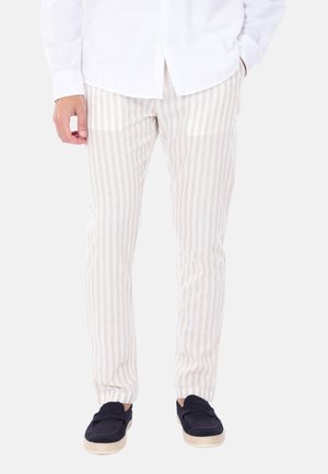 Pantaloni a righe beige chiaro realizzati in un morbido tessuto, con righe verticali e una vestibilità slim. Abbinati a scarpe slip-on blu navy.