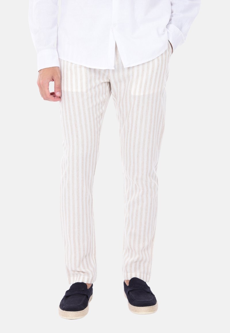 Pantaloni a righe beige chiaro realizzati in un morbido tessuto, con righe verticali e una vestibilità slim. Abbinati a scarpe slip-on blu navy.